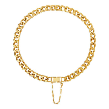 A gold-colored choker necklace with a curb chain design and a small gold extender chain attached to it.