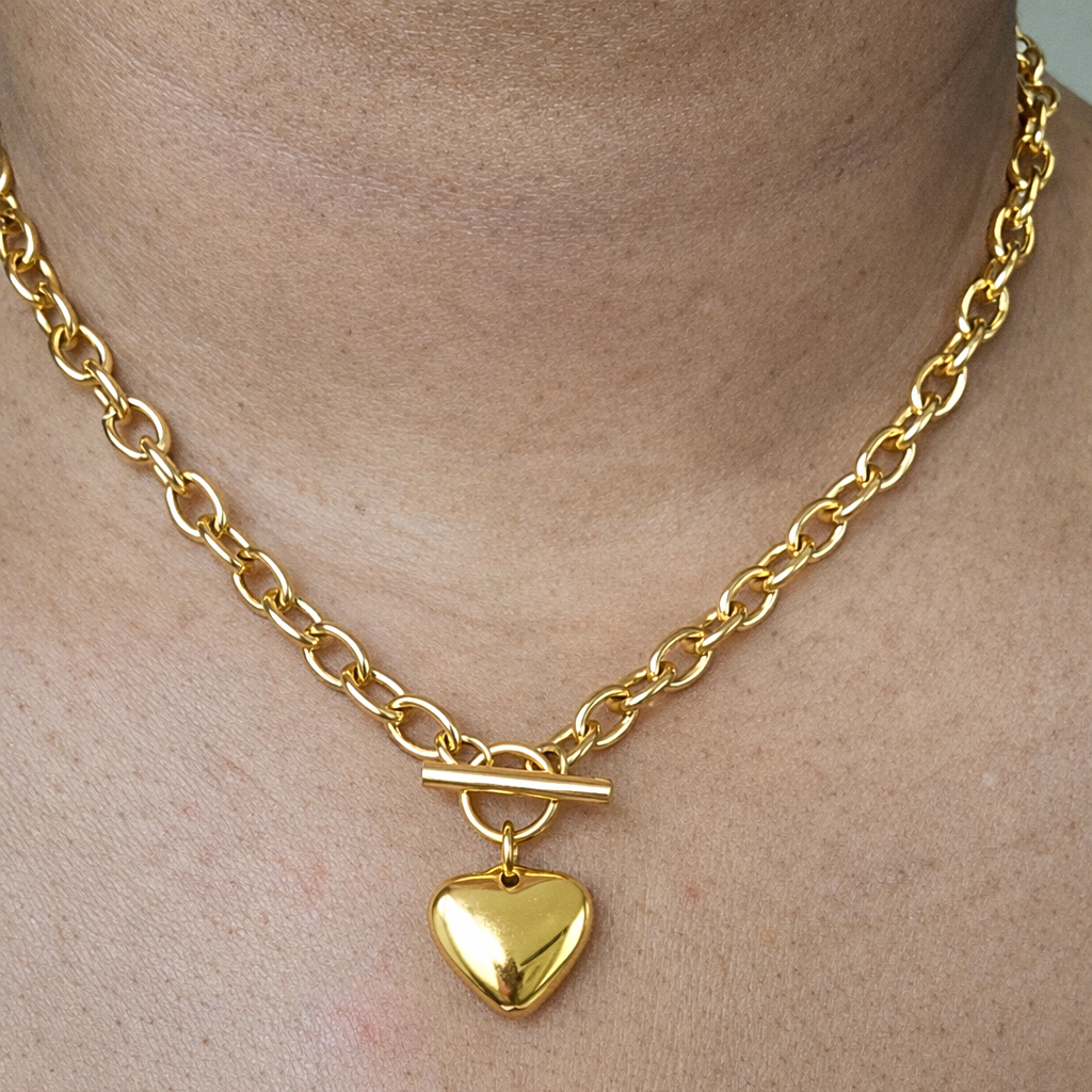 Front view Gold link chain necklace with a heart-shaped pendant on a models neck.