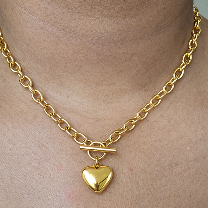 Front view Gold link chain necklace with a heart-shaped pendant on a models neck.