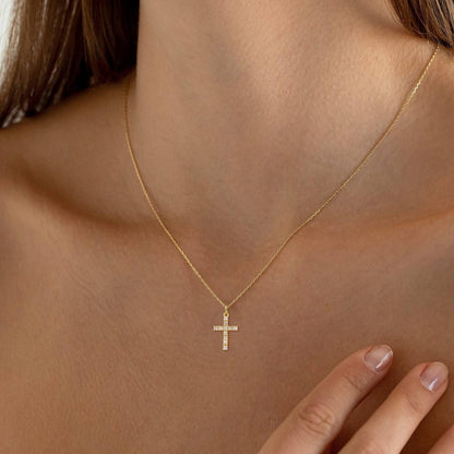 A model wearing a waterproof gold jewelry cross,  with cubic zirconia 