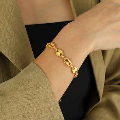 Gold chain bracelet on a wrist with a neutral background
